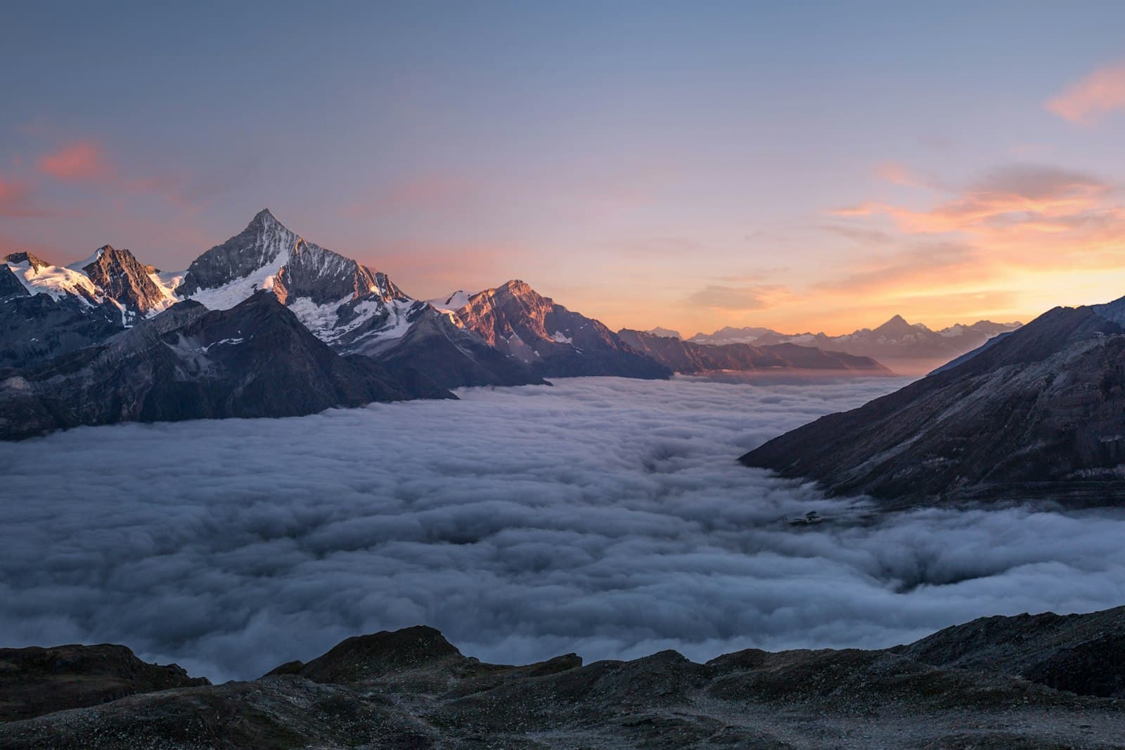 Sunrise over mountain peaks rising above a sea of clouds