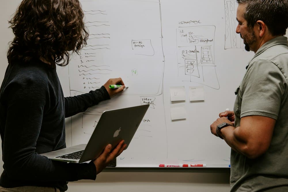 Two colleagues planning ideas on a whiteboard