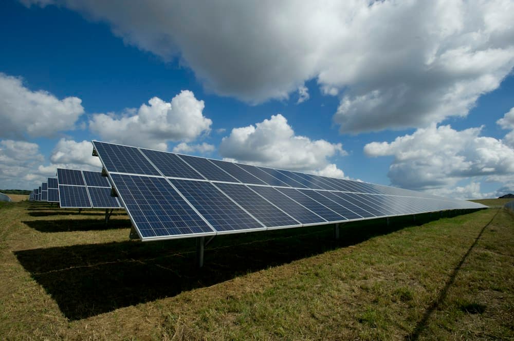 Solar panels in a green field under a blue sky