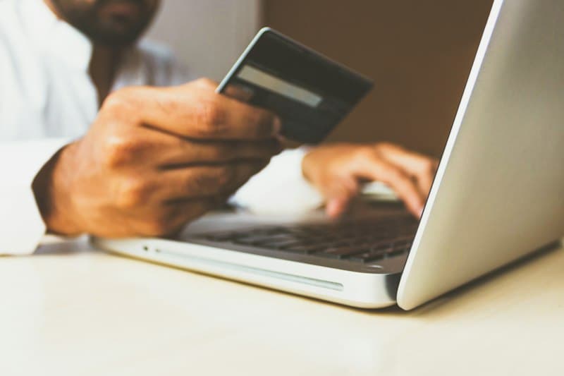Person shopping online with a payment card and laptop