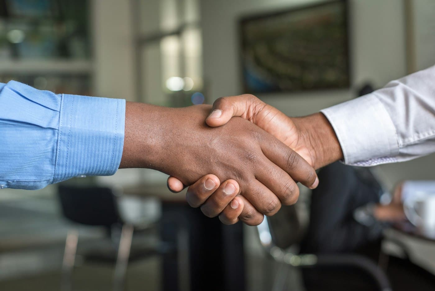 Two business people shaking hands across a table