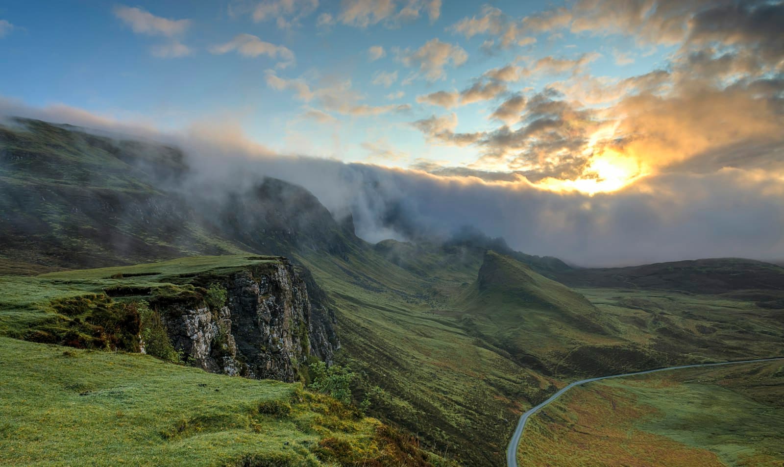 Misty green valley and hills at sunrise
